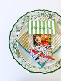 Beautiful table setting with a green and white floral plate, yellow striped napkin, floral card, and a 'Best Day Ever' tag in green and white stripes, set on a white table