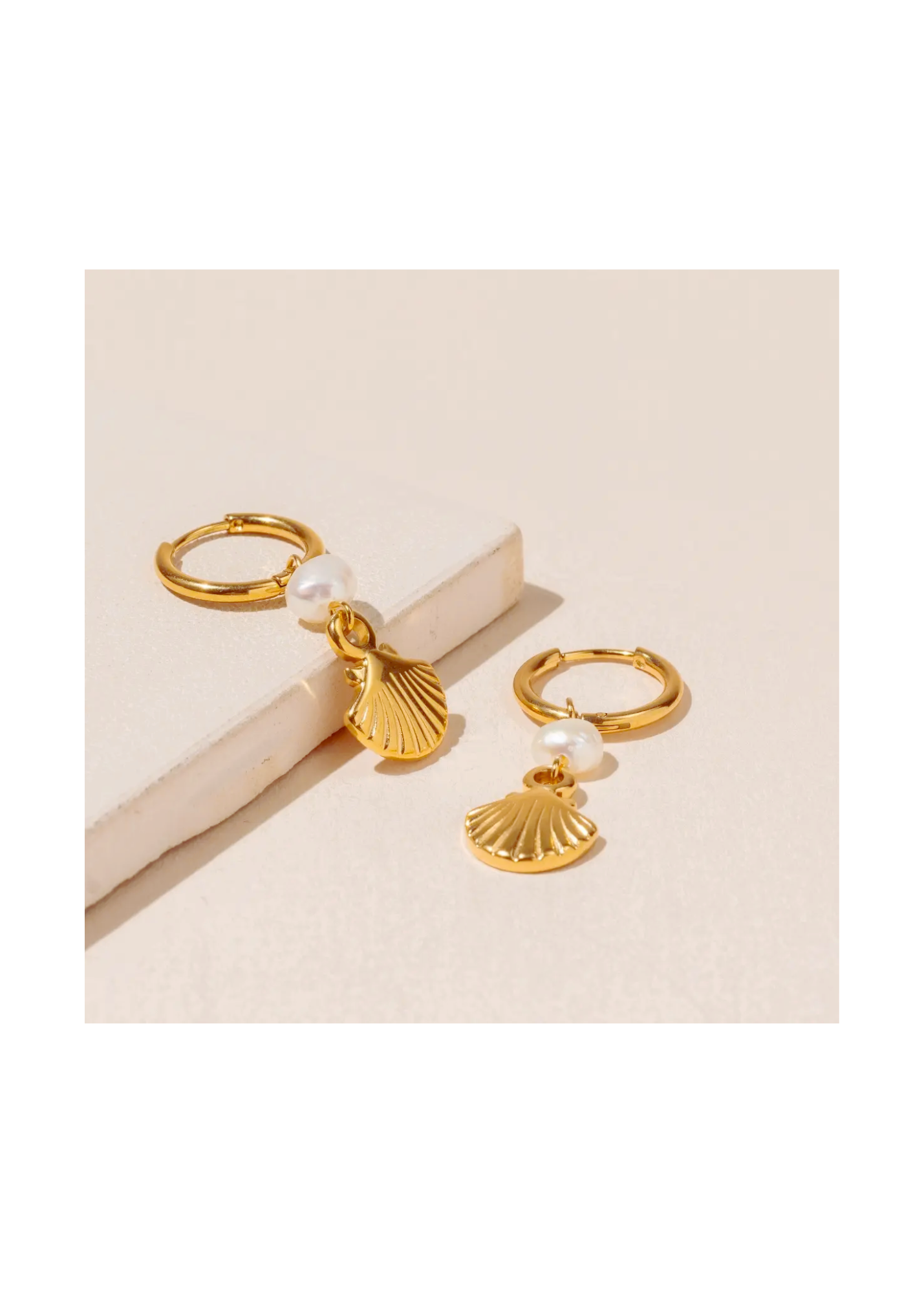 1.3-inch Shell and Pearl Earrings with 18K gold plating and durable stainless steel. A luxurious accessory designed to elevate any outfit and occasion posed on an elegant backdrop