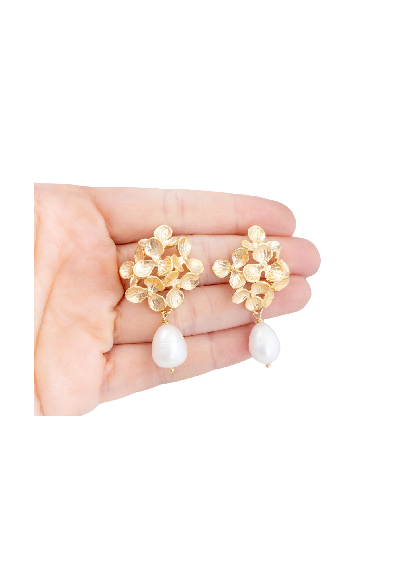 Elegant gold and pearl drop earrings with floral design, resting in a hand for scale and detail.