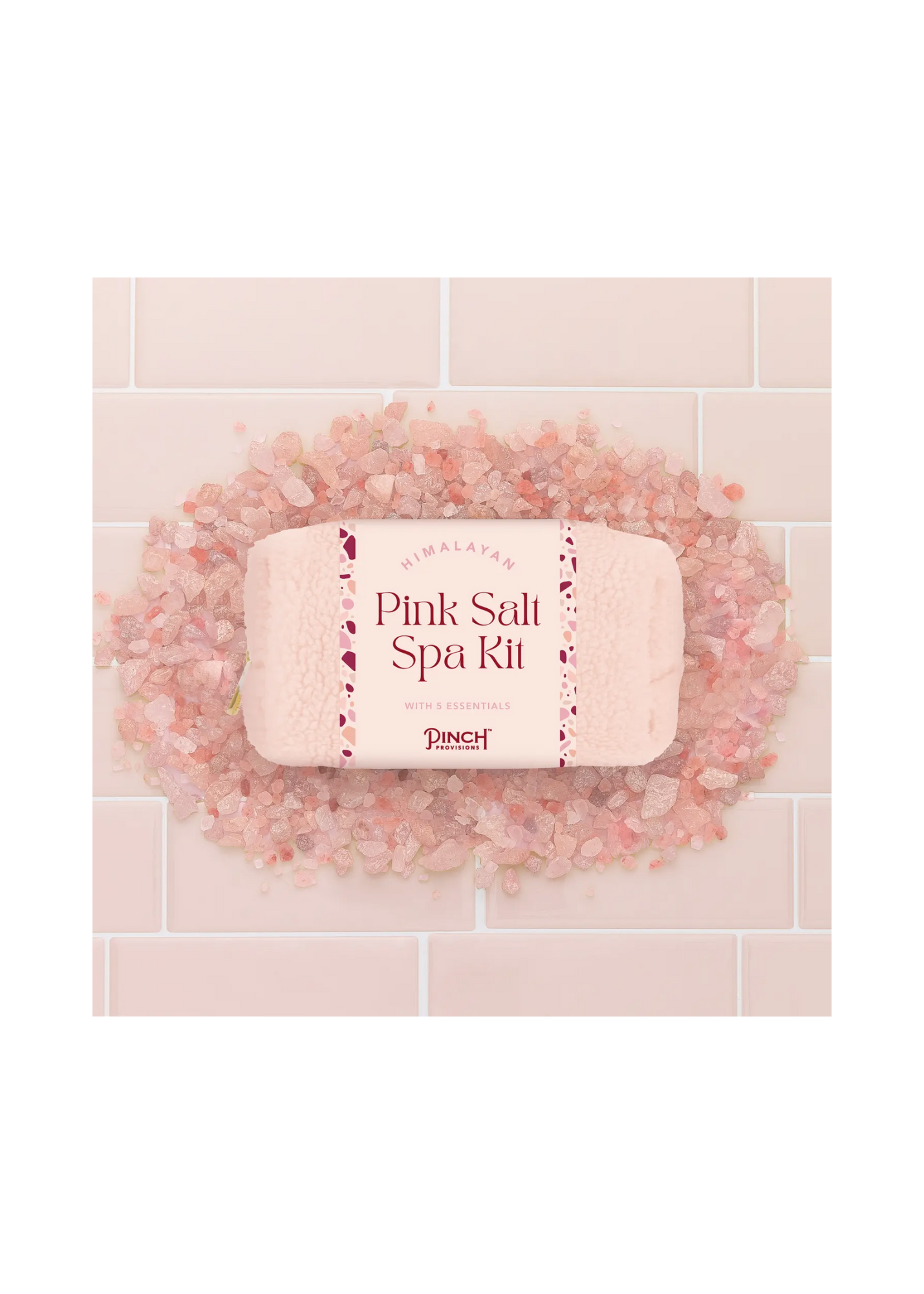 Himalayan pink salt spa kit by Pinch Provisions, featuring a cozy pouch surrounded by pink salt crystals on tiled background.