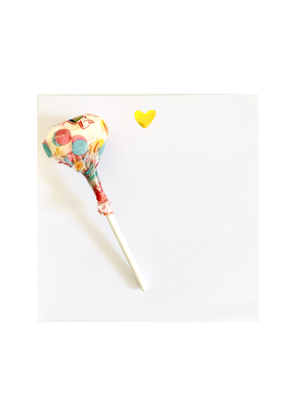 The Note Taker" pad with 50 high-quality sheets features an elegant gold foil heart design for notes and doodles. Includes a single Smarties Pops Lollipop offering a blend of two classic flavors, perfect for enjoying while jotting down thoughts.